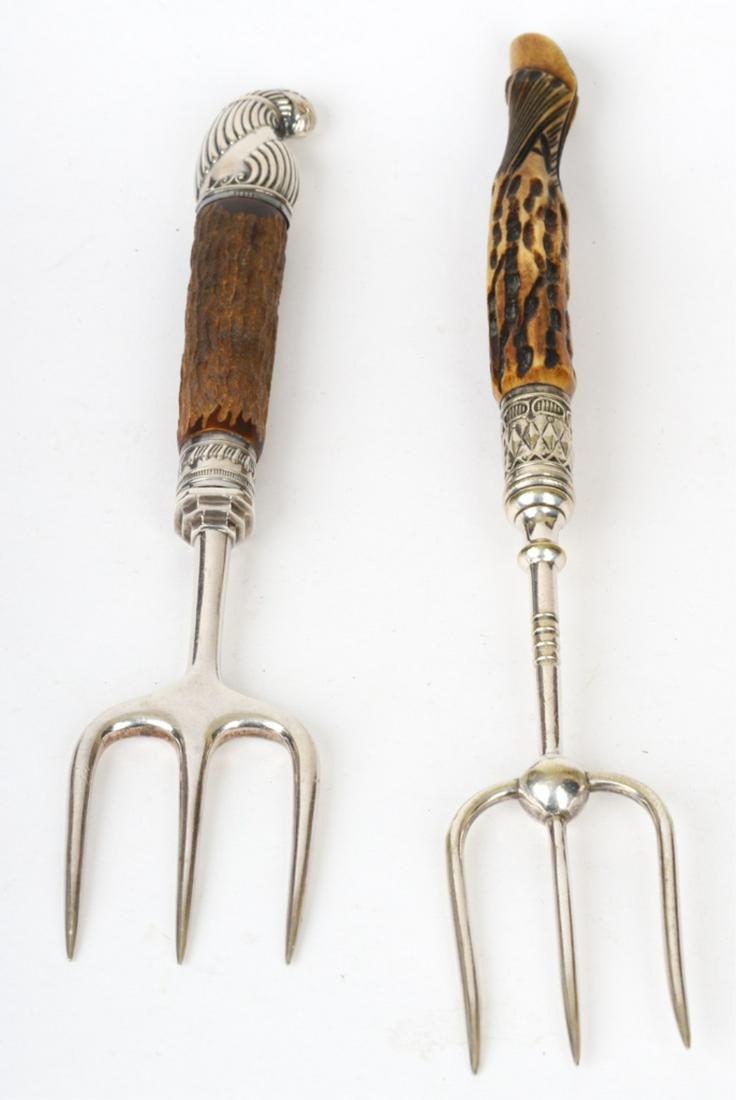 (2) INTERESTING BREAD FORKS: (1) Chipped wooden handle mounted with sterling silver ferrule and end and the second with an antler handle carved with a hoof. 8 and 9 1/2 inches.