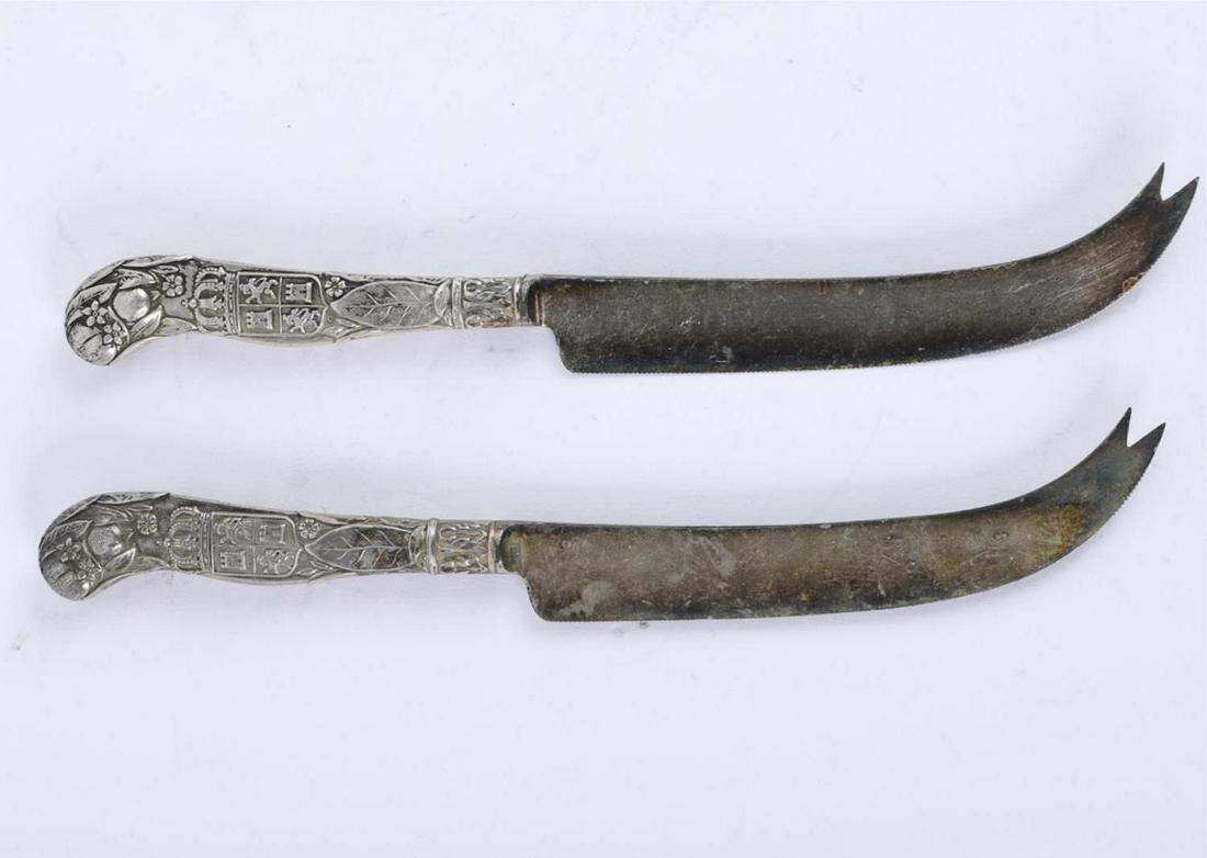 PAIR OF GORHAM SILVER CHEESE KNIVES: Sterling silver handles embossed with castles, heraldry, fruit and flora. 8 1/2 inches