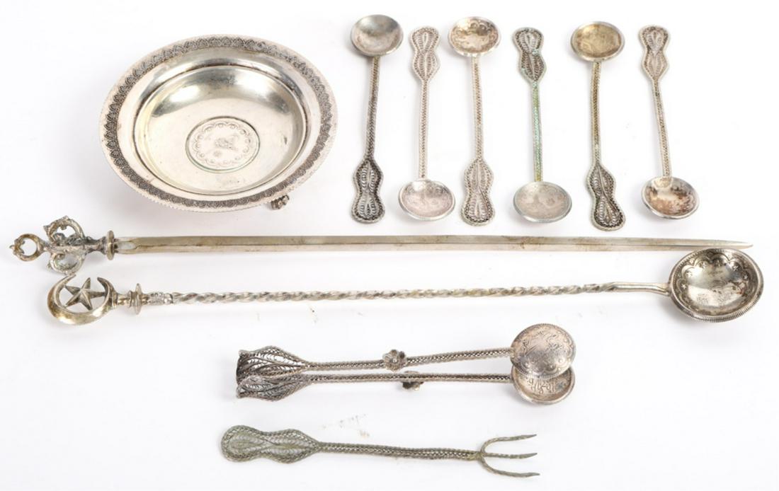 GROUPING of TURKISH / OTTOMAN SILVERWARES: Including: Small dished plate raised on (3) lion paw feet, skewer marked 800, long handled spoon with coin bowl, and (8) silver filigree spoons, fork and tongs. 11 inches (and under). 5.2 troy ounces