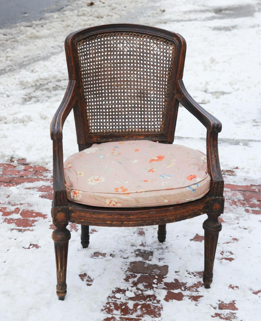LOUIS XV CANE BACK ARMCHAIR: Molded frame with scrolled arms and turned and reeded legs. Upholstered cushion is supported on stretched burlap straps.