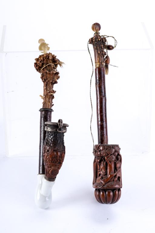 (2) HEAVILY CARVED GERMAN / BLACK FOREST PIPES: Bowl with hinged lid is carved with a coaching scene, affixed with a porcelain transition and topped with a natural antler. The second is carved with a hunting scene and scalloped scroll and affixed w