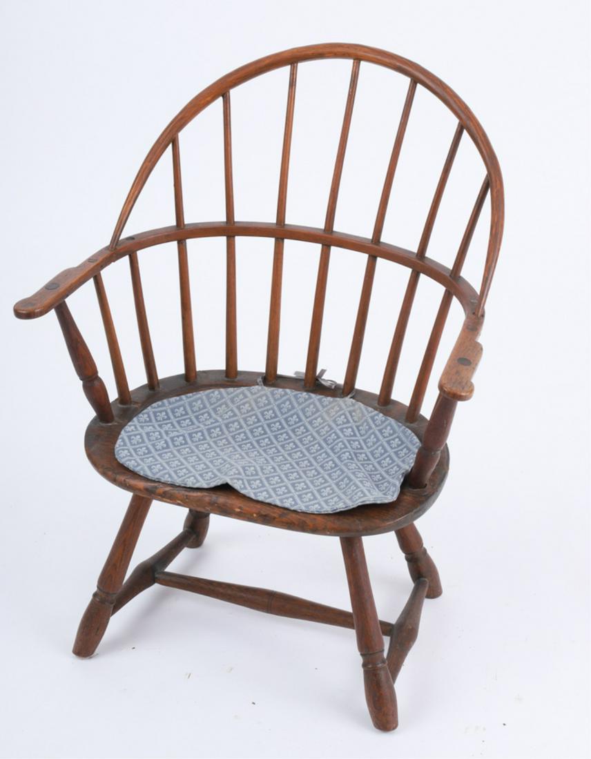 EXCEPTIONAL CHILD'S BOW-BACK WINDSOR ARMCHAIR: American with scooped pine seat, splayed turned legs joined by stretchers, the underside shows traces of early black and red paint, as well as a partial owner's label, late 18th to early 19th century,