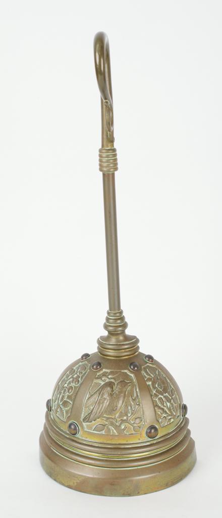 ENGLISH BRASS WEIGHTED DOORSTOP: Scroll handle above a domed base with a relief of a bird in a tree, late 19th century, 16 x 6 x 3