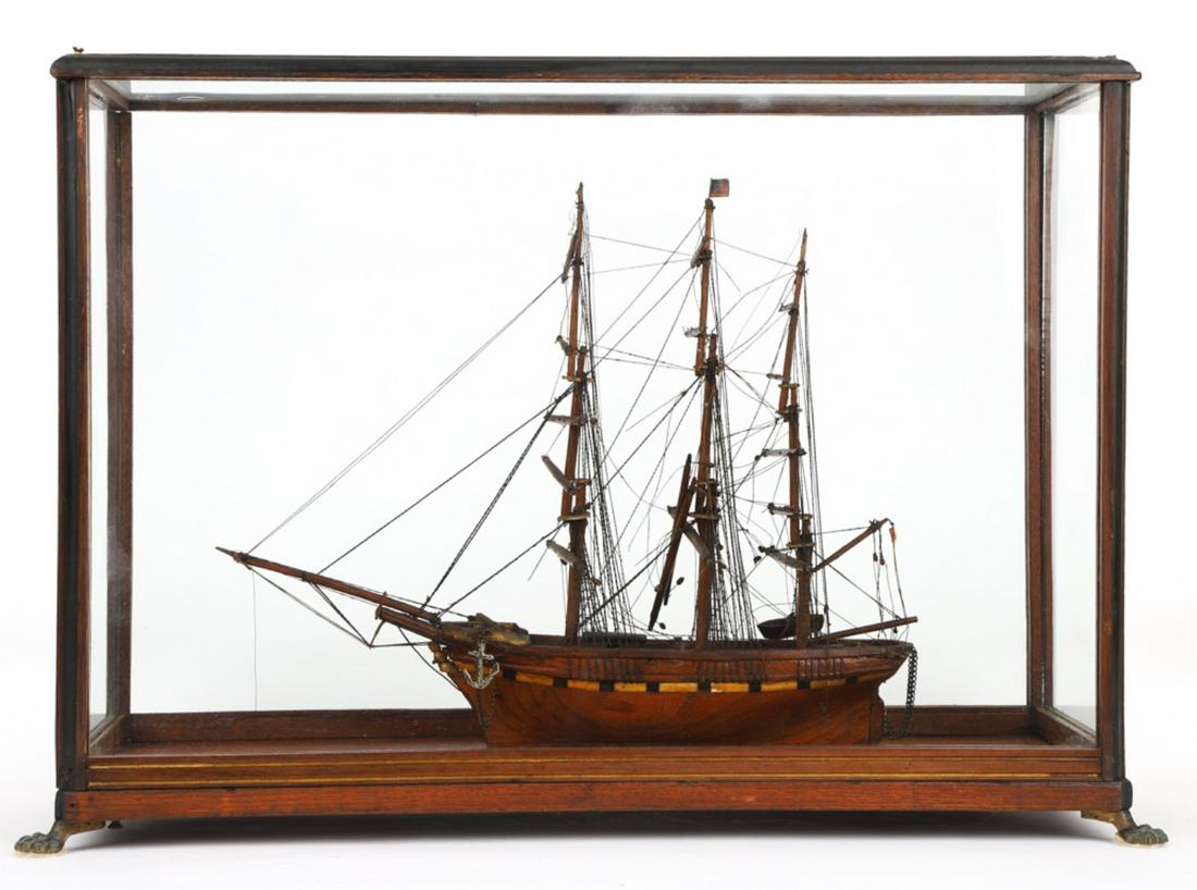 THREE MASTED CASED SHIP MODEL: Late 19th century, the hull appears to be made from elm, with an inlaid border and a carved figurehead, approximately 11 x 13 inches, case with brass claw feet, 14 x 20.5 x 8 inches