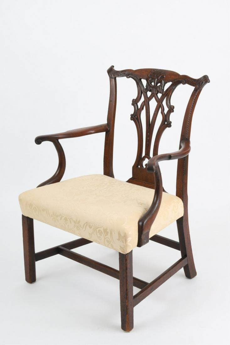 CARVED MAHOGANY CHIPPENDALE ARMCHAIR: Ornately carved crestrail and pierced splat, scrolled arms above a upholstered tight seat, raised on Marlborough legs joined by stretchers, 18th century, 38 x 28 x 20.5 inches