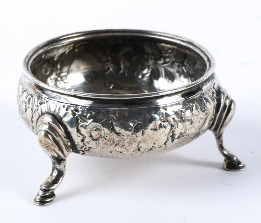 STERLING SILVER MASTER SALT BY GEORGE SMITH: Font hand chased with floral motif is raised on (3) legs with hoof feet. 1 1/4 x 2 1/4 inches 1.11 troy ounces. Condition: Good Temp No 6072