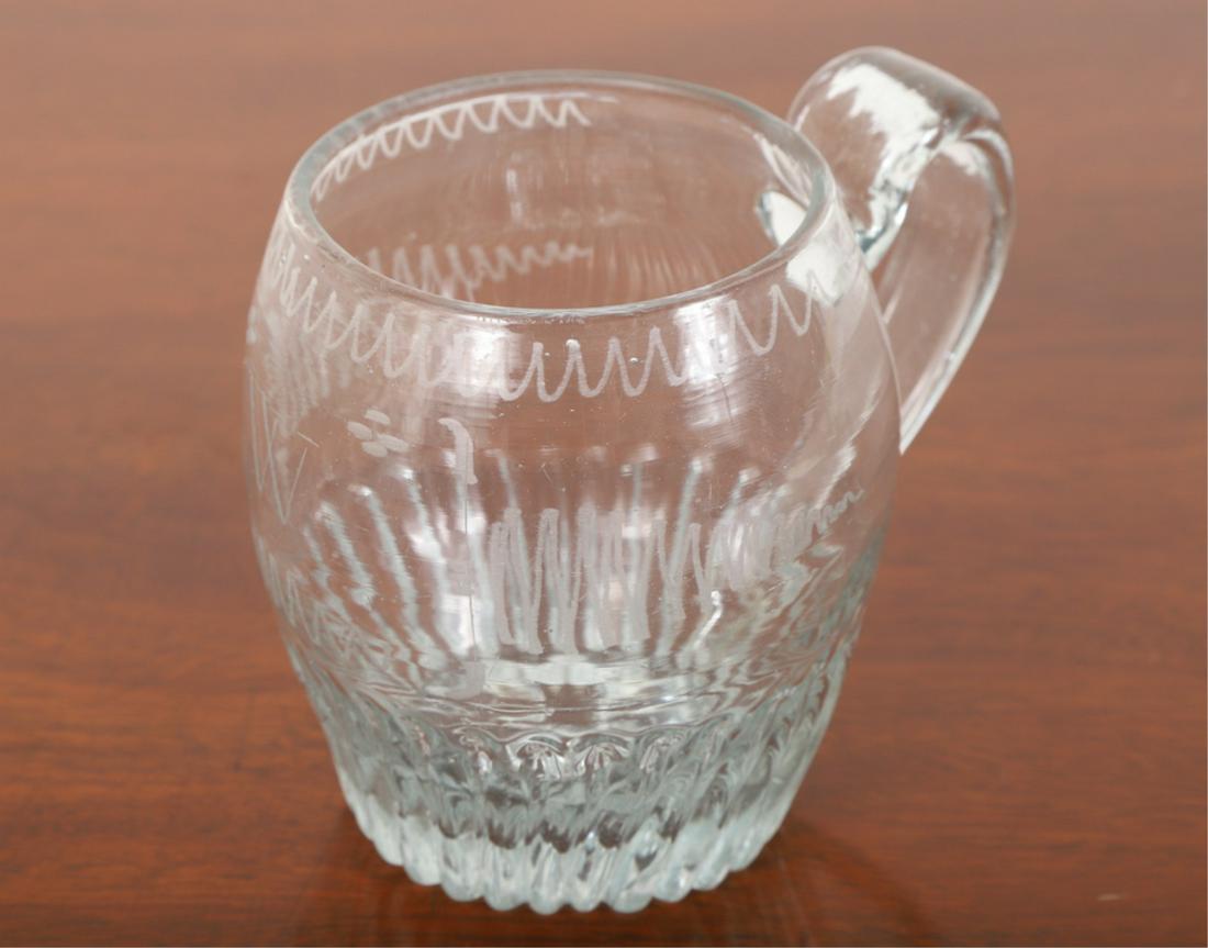 (20th c) BARREL-FORM ENGRAVED GLASS MUG: Applied strap handle, wrigglework bands frame the letter "W". 3 3/4 inches