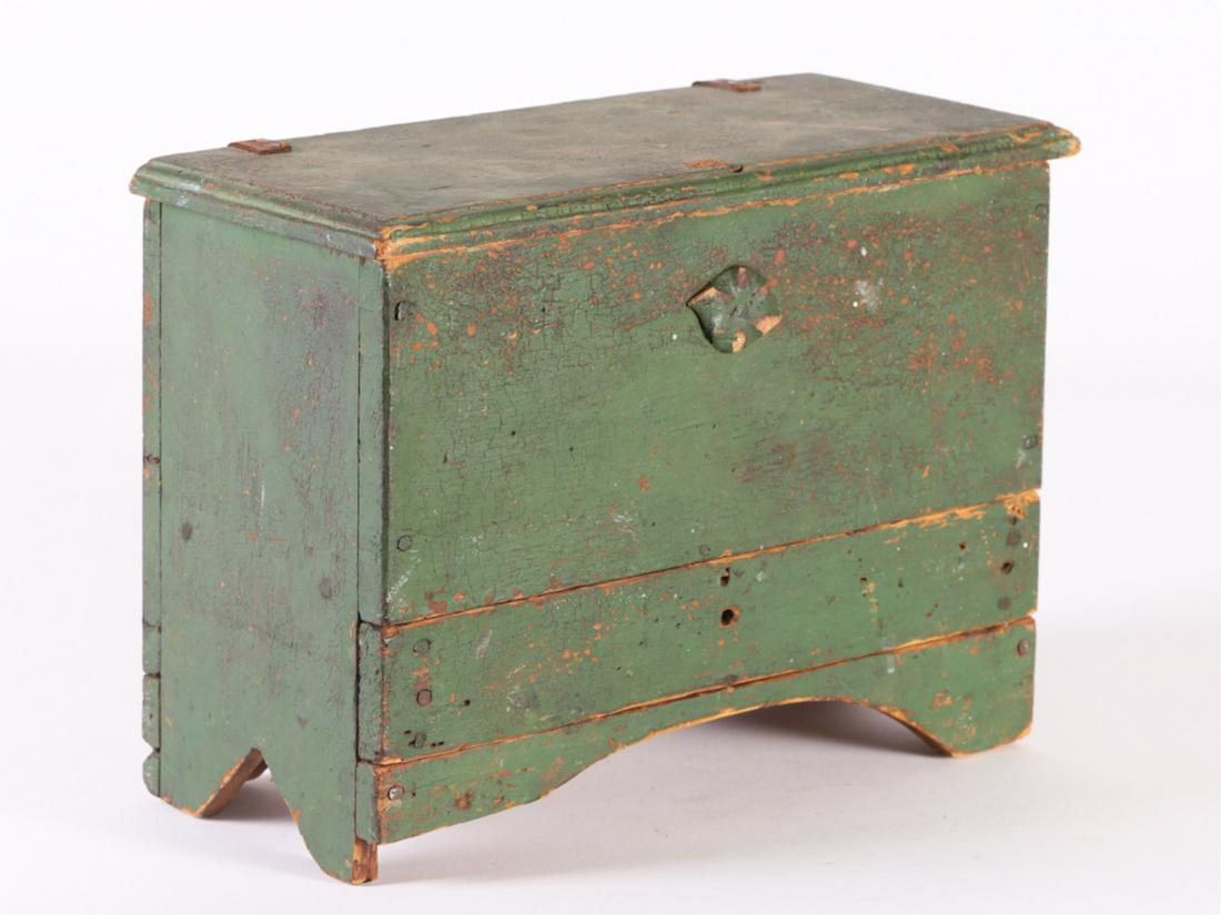 MINIATURE (1) DRAWER BLANKET CHEST IN GREEN PAINT: (Early 19th c) Molded lid with remnants of snipe and leather hinges, bootjack ends and arched apron. 9 1/4" x 12 3/4" x 5 3/4"