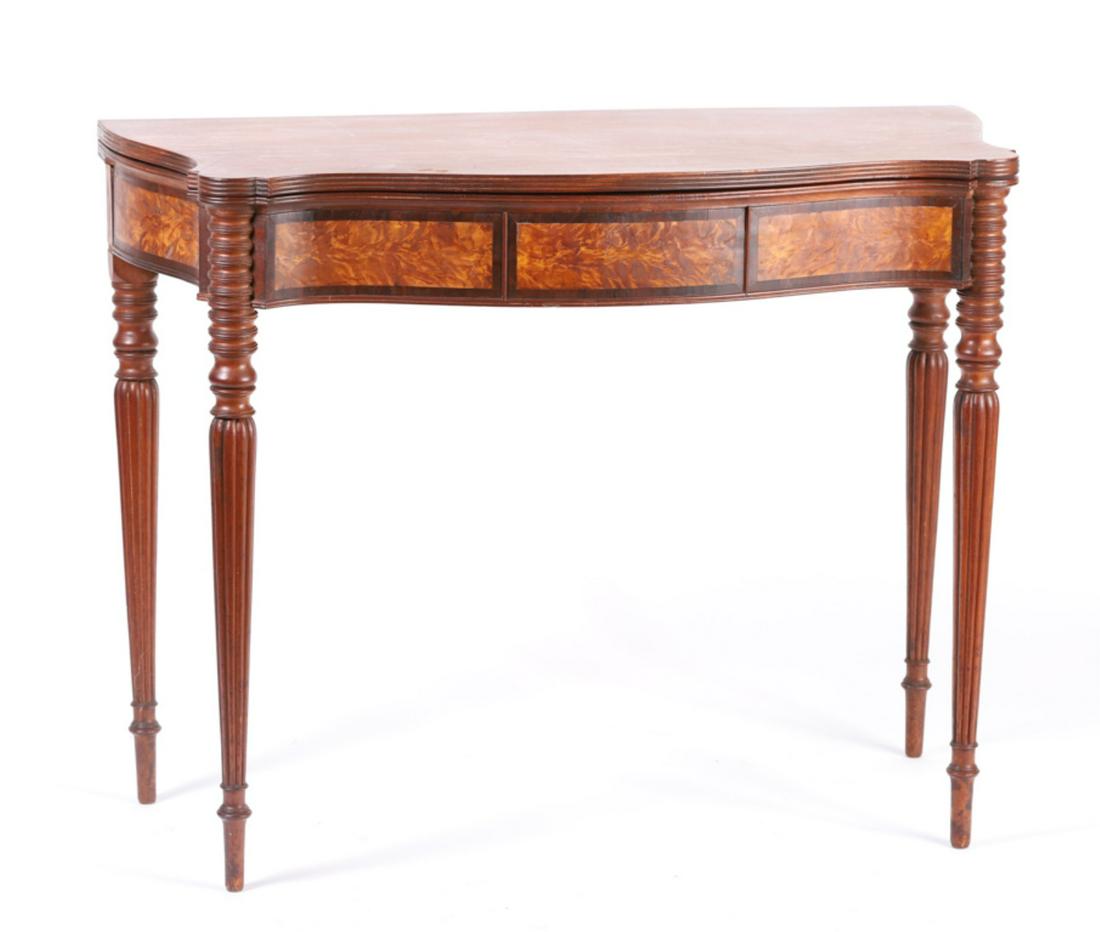 SEYMOUR SCHOOL SHERATON MAHOGANY CARD TABLE: Molded serpentine turret top with conforming molded apron inlayed with flame birch and mahogany raised on tapering turned and reeded legs. 29 1/2 x 38 x 18 inches.