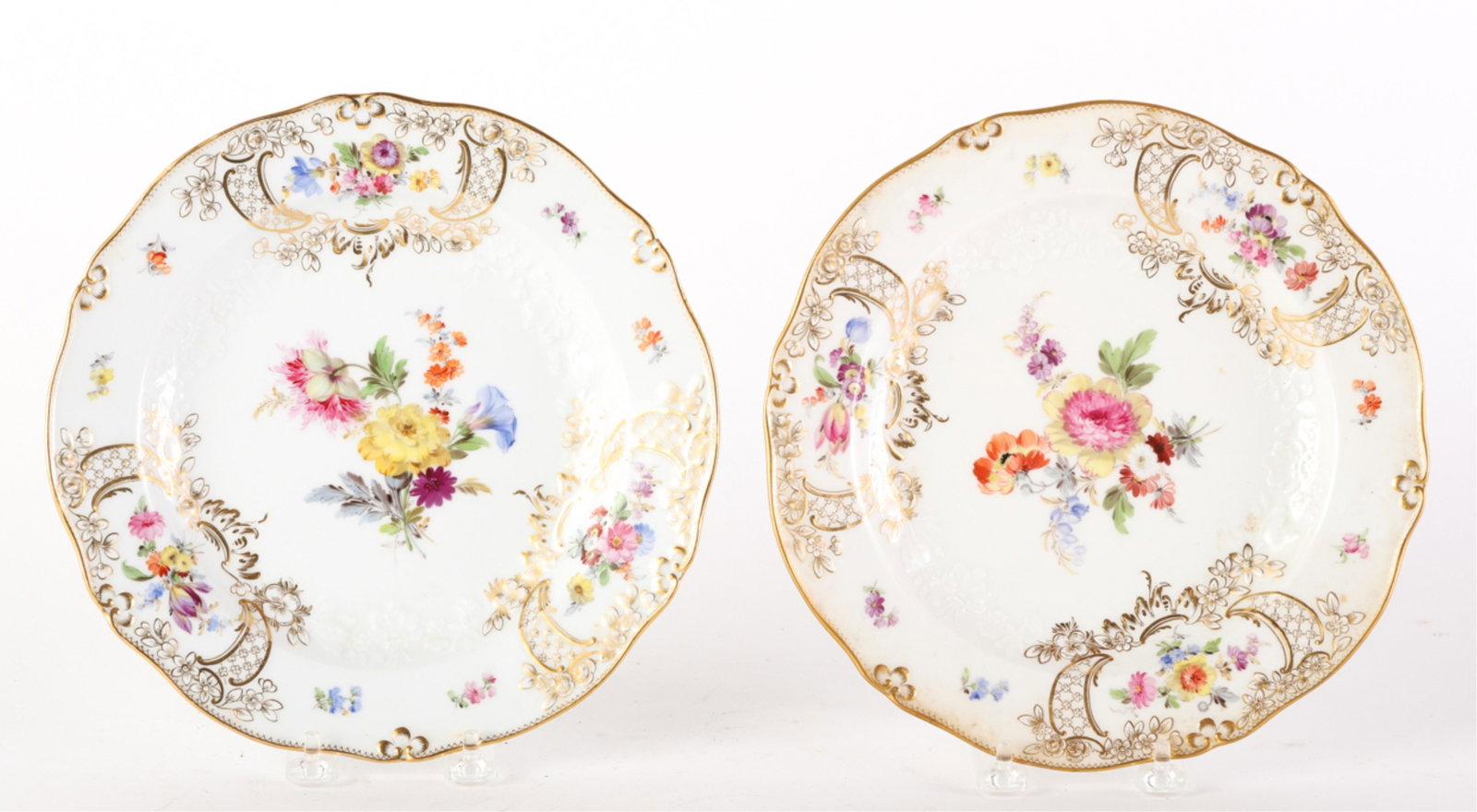 PAIR OF MEISSEN DISHED PLATES with FLORAL MOTIFS: Porcelain molded with raised flowers as well as hand painted examples amongst cartouches of gold filigree with diaper patterns. 9 1/2 inches