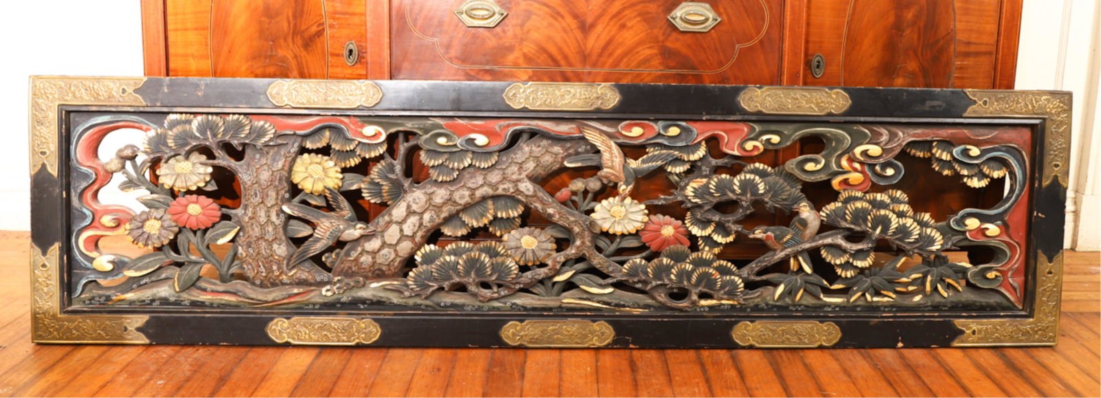 CHINESE BRASS BOUND CARVED AND PIERCED WOOD PANEL: Depicting birds within flowering trees under clouds. 17 x 75 inches