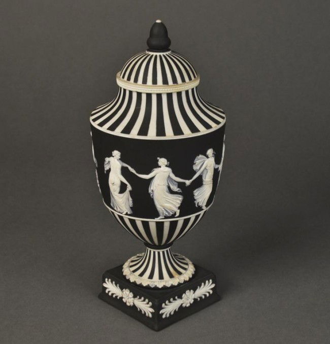 Black and white stiped covered urn with classical: Black and white stiped covered urn with classical figures, ""Dancing Hours"" on a square base, Wedgwood Made in England mark. Height: 10""