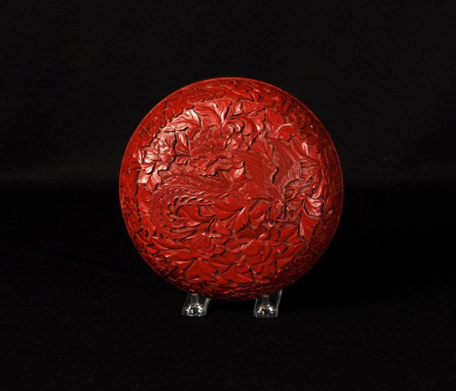 Asian Cinnabar laquer covered box: Asian Cinnabar laquer covered box, probably early 20th C carved and undercut with a phoenix amid lush flowering peony bushes. Diameter: 7"