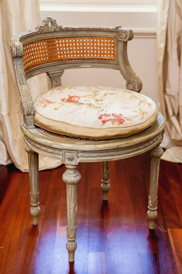 LOUIS XVI STYLE BOUDOIR CHAIR: Wonderfully carved throughout with wreath, bow, ropes, overlapping scales, acanthus leaves and florets. Cane back and seat with a floral embroidered cushion. 29 x 19 x 19 inches Condition: Scattered f