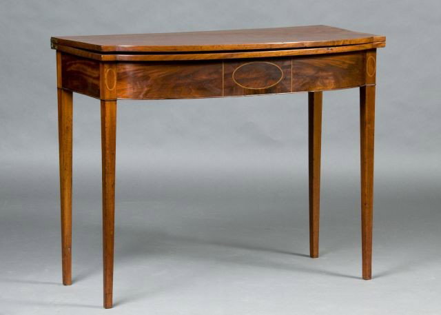North Shore Hepplewhite mahogany card table: circa 1790 having outset bowed front, apron centered with patera and string inlays the whole rising on square taper legs, 28" X 35 1/2" X 17 1/2"