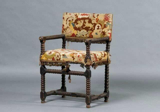 Cromwellian open armchair with spool turnings: upholstered in needlepoint centered with a petitpoint of a royal crest, 34"h x 22" w x 16"d