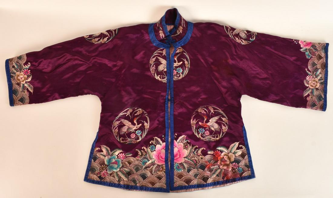 CHINESE EMBROIDERED SILK JACKET: Plum silk jacket embroidered with cranes, birds and floral motifs. Collar to waist 26 inches. Center of collar to cuff 26 inches Condition: Good, light stain behind back of sleeve. Light wear to end o