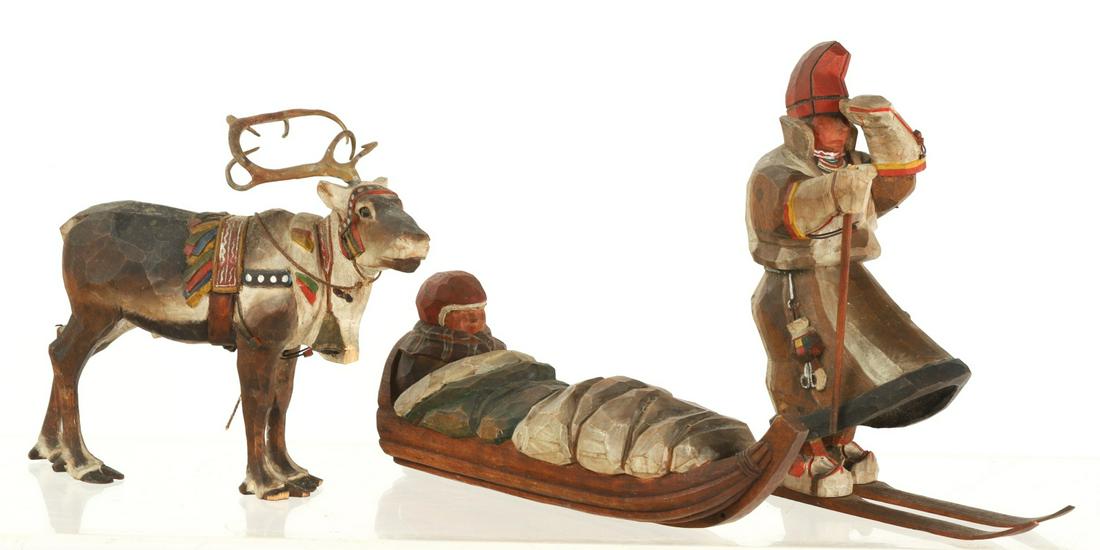 ERIC ELENIUS (1885-1940) LAPLAND RESCUE: (3) carved and painted figures by Eric Elenius depicting a man being rescued in a sled pulled by a reindeer and guided by a man on skis. (2) men signed "Eric Elenius Svergie", reindeer unsigned. Skier