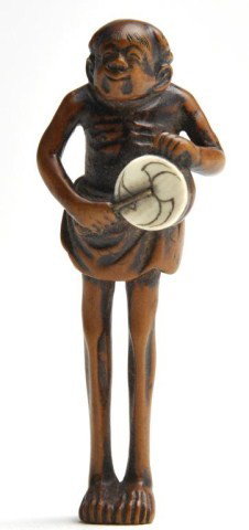 Japanese carved wooden netsuke of a tall man: Japanese carved wooden netsuke of a tall man beating an ivory drum. H: 2 3/4"