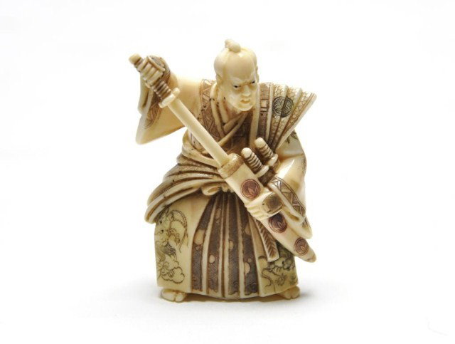 Early 20th century Japanese ivory netsuke of a war: Early 20th century Japanese ivory netsuke of a warrior with sword, signed. H: 2 1/8"