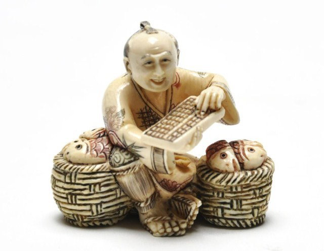 Early 20th century Japanese ivory netsuke of man: Early 20th century Japanese ivory netsuke of man with baskets and money drawer, signed. H: 1 1/2"