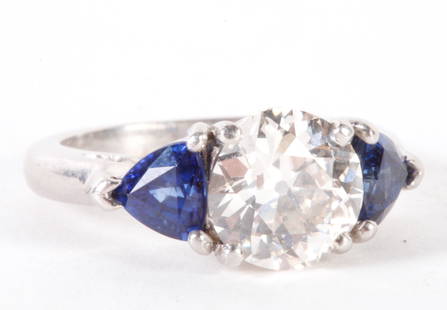 2.5 CARAT DIAMOND and SAPPHIRE RING: Platinum ring set with 8.7mm 2.5ct VS 2 K-L color diamond flanked by (2) 5mm trillion cut sapphires approx. .33ct each. 4.7dwt size 5. Provenance: Firestone & Parson, Newbury St, Boston.