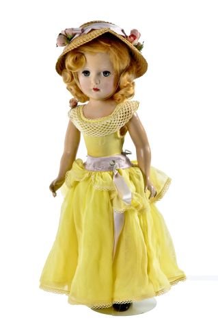 18 inch Cissy doll, wearing dress of yellow: overskirt - over yellow underskirt, matching underwear, knee length nylons, black shoes, straw bonnet with matching ribbon of purple sillk and flowers, flowers on waist - sash missing. Some soiling on