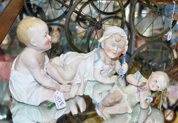 Three bisque Piano Babies; 1 baby in white dress: & bonnet ( 11 1/2" long x 5 1/2" tall ) #557,# 2 seated baby in white ( 8 1/2" tal l- may have markings but felt on bottom)# 3 - Smaller baby in yellow - 7 1/2" long
