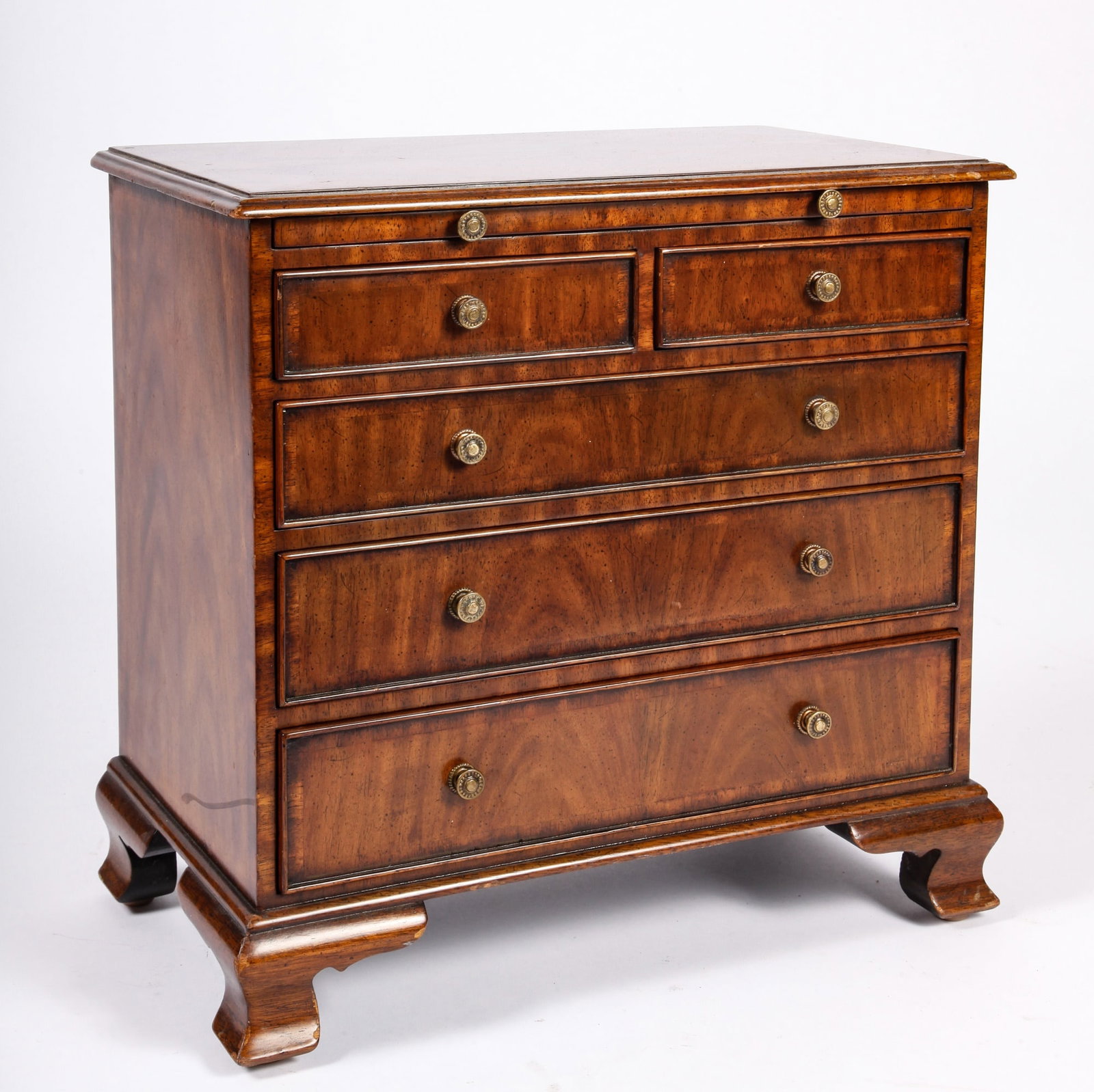 MINIATURE MAITLAND-SMITH WALNUT BUTLER'S CHEST: Case of banded and match-book veneer, molded top, butler's pullout shelf, cock-beaded drawers, applied molded base and ogee bracket feet. 15 x 16 x 9 inches. Provenance: Knox Mansion / Orchard House 8