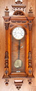 MONUMENTAL VIENNA  WALNUT REGULATOR WALL CLOCK: 7 inch dial with spring wound pendulum movement . Finely carved walnut case 55 x 19 x 7 1/4 inches