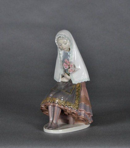 Lladro figure of a young woman seated, holding flo: Lladro figure of a young woman seated, holding flowers. H: 10"