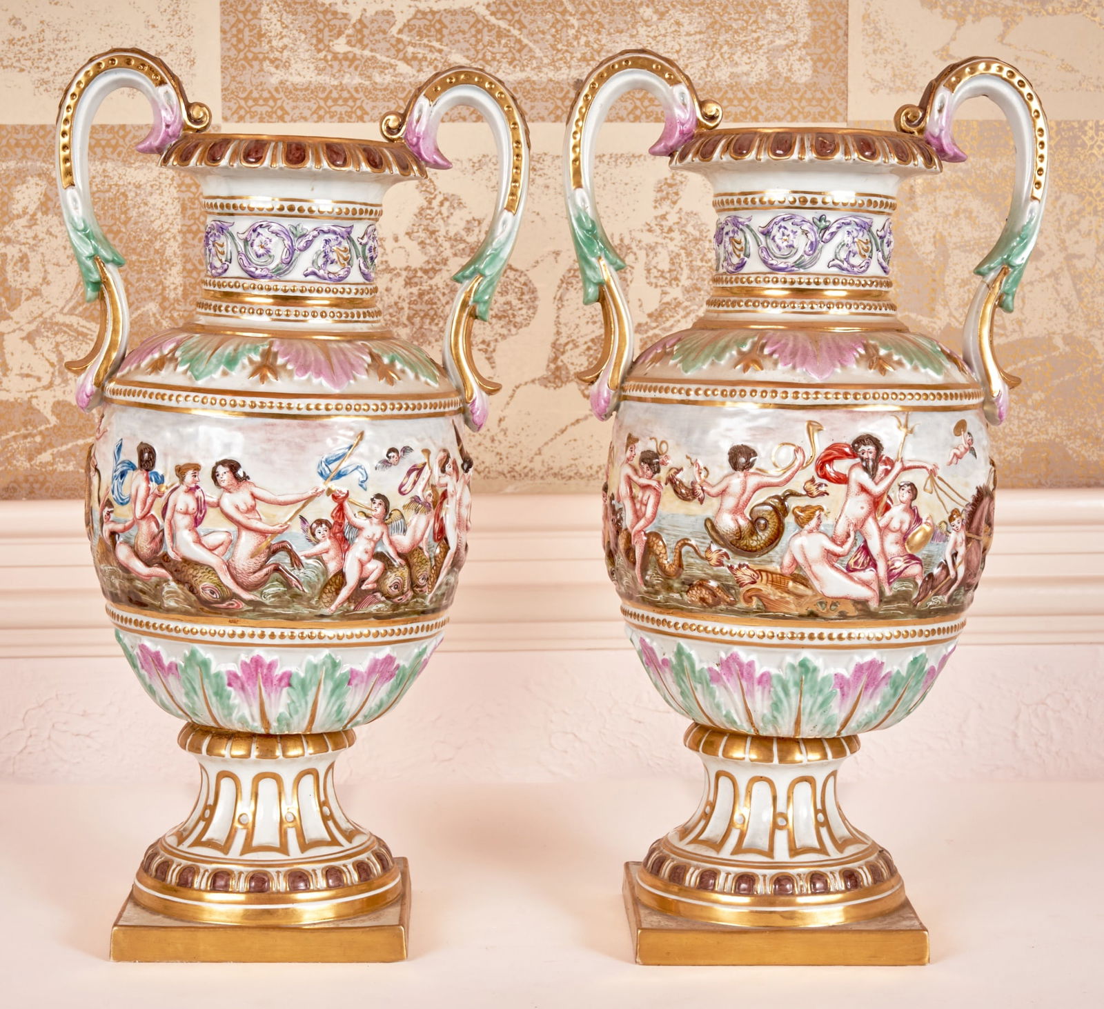 PAIR of POLYCHROME CAPODIMONTE NEPTUNIAN VASES: Beautiful pair of Capodimonte vases with applied handles & Neptunian figures in relief around the body. 16 x 8 x 6 inches. Condition: Repair to handle. Temp No 3045