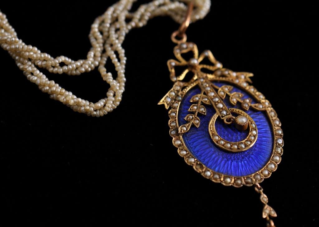 An Edwardian 9K Gold Pendant on Pearl Chain: Deep blue pendant decorated with pearl set foliate design, chain of natural seed pearls, weight 5.6 dwt Condition: good Size: pendant 2 5/8" on 16" chaingoodpendant 2 5/8" on 16" chain