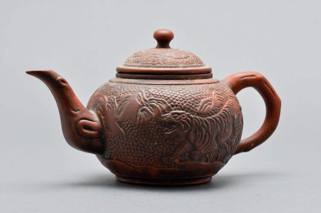 (19th c.) Chinese Teapot: Redware teapot decorated in relief with two tigers in a landscape. Signed with a character on bottom, Condition: surface grime Size: 5" x 9" x 5"surface grime5" x 9" x 5"