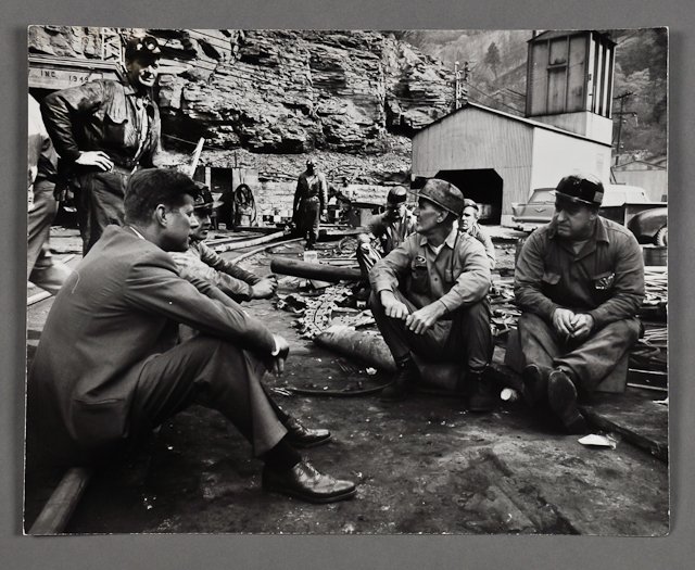 1960-May, J.F.K. Campaigns in West Virginia: (1) Large format photograph for "Life" Magazine, of J.F.K. sitting down with coal miners, 10 1/2" x 13", taken by Hank Walker. Condition: Good, minor creases