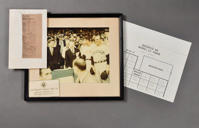 1961-April 10, "President Kennedy, Baseball": (1) Color photograph of J.F.K. and Dave Powers at the 1961 baseball opener on April 10, the Chicago White Sox vs. the Washington Senators, 7 1/2" x 9", framed, with a card commemorating the event with