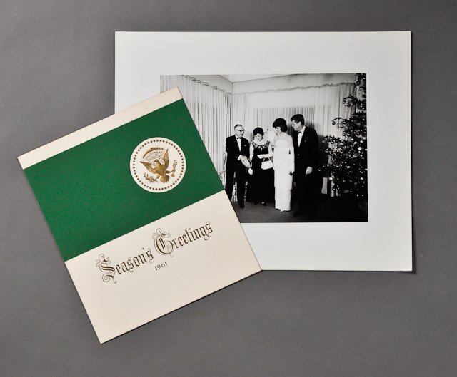 1961-Dec, J.F.K. and Jackie, Christmas: (1) Formal "Season's Greetings 1961" card, from "The President and Mrs. Kennedy," 7" x 6". Toning. Together with (1) photograph of the Kennedys with guests, 8" x 10", taken by Cecil W. Stoughton. Good