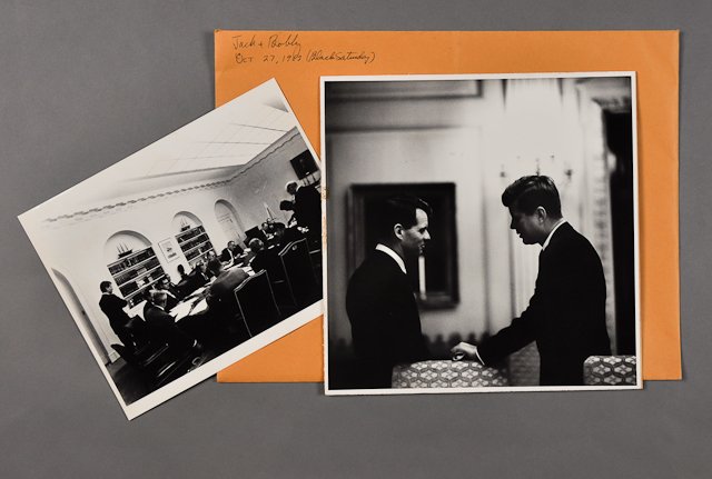 1962-Oct 29, J.F.K., Cuban Missile Crisis: (1) Photograph of J.F.K. with Bobby Kennedy, 11" x 11". Mounted, soiling. (1) Photograph of a high level meeting on Oct 29, 8" x 10", taken from the Kennedy Library. Condition: See Description