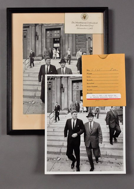 1962-Nov 1, J.F.K., All Saints Day: (1) Photograph of J.F.K. with Dave Powers in front of St. Matthew's Cathedral, Nov 1, 9" x 7". Mounted and framed, together with a card with the Great Seal of the President annotating the event. (1) P