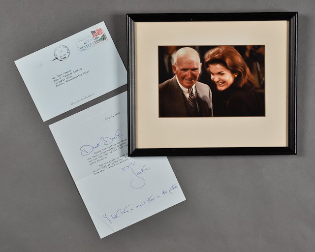 1990-July 9, Jackie Signed Note, Photograph: (1) Page note with envelope to Dave Powers from Jackie thanking Dave for telling her about the Peace Corps exhibit. July 9. Signed "XXX Jackie, You look like a movie star in the picture". Together wit