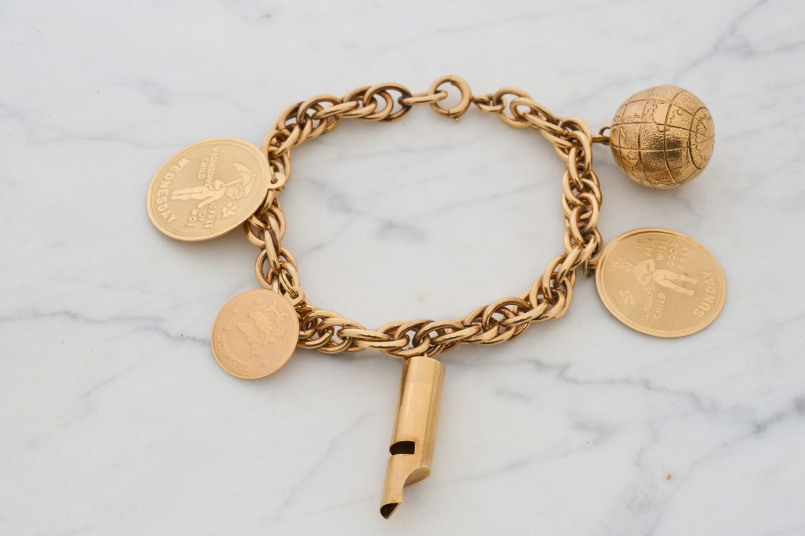 14k GOLD CHARM BRACELET w (5) CHARMS: Globe, whistle, Sunday's Child, Pisces and Wednesday's Child. All hallmarked except for globe (tested at 14k). Bracelet measures 8 1/2 inches. 37.3 dwt. Condition: Good. Some personalized. Temp No 765