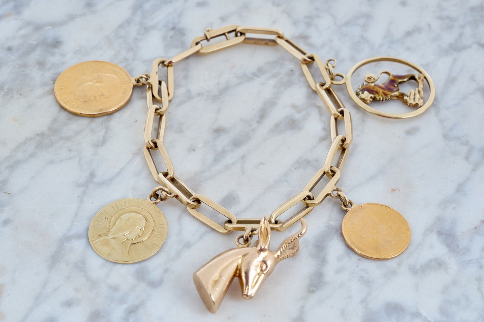 14K GOLD PAPERCLIP CHAIN CHARM BRACELET w CHARMS: (2) Dutch coins, gazelle, Madonna and lion with enamel. 8 1/8 inches. 30.95 dwt. Condition: Some enamel missing. (1) personalized. Temp No 8005