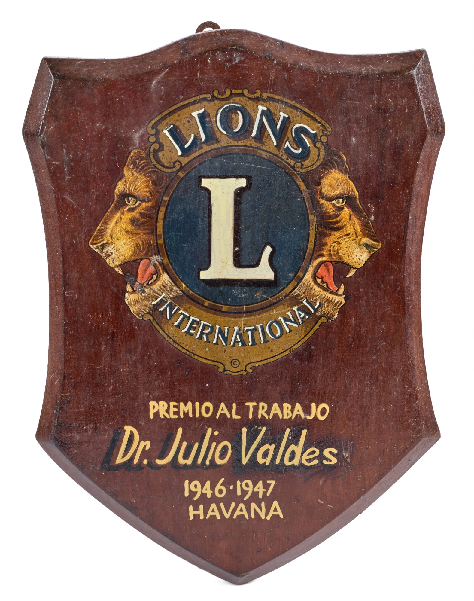 LIONS INTERNATIONAL WORK AWARD PLAQUE / HAVANA: Paint highlighted decal on mahogany. 13 1/2 x 9 1/2 inches Condition: Wear Temp No 7707