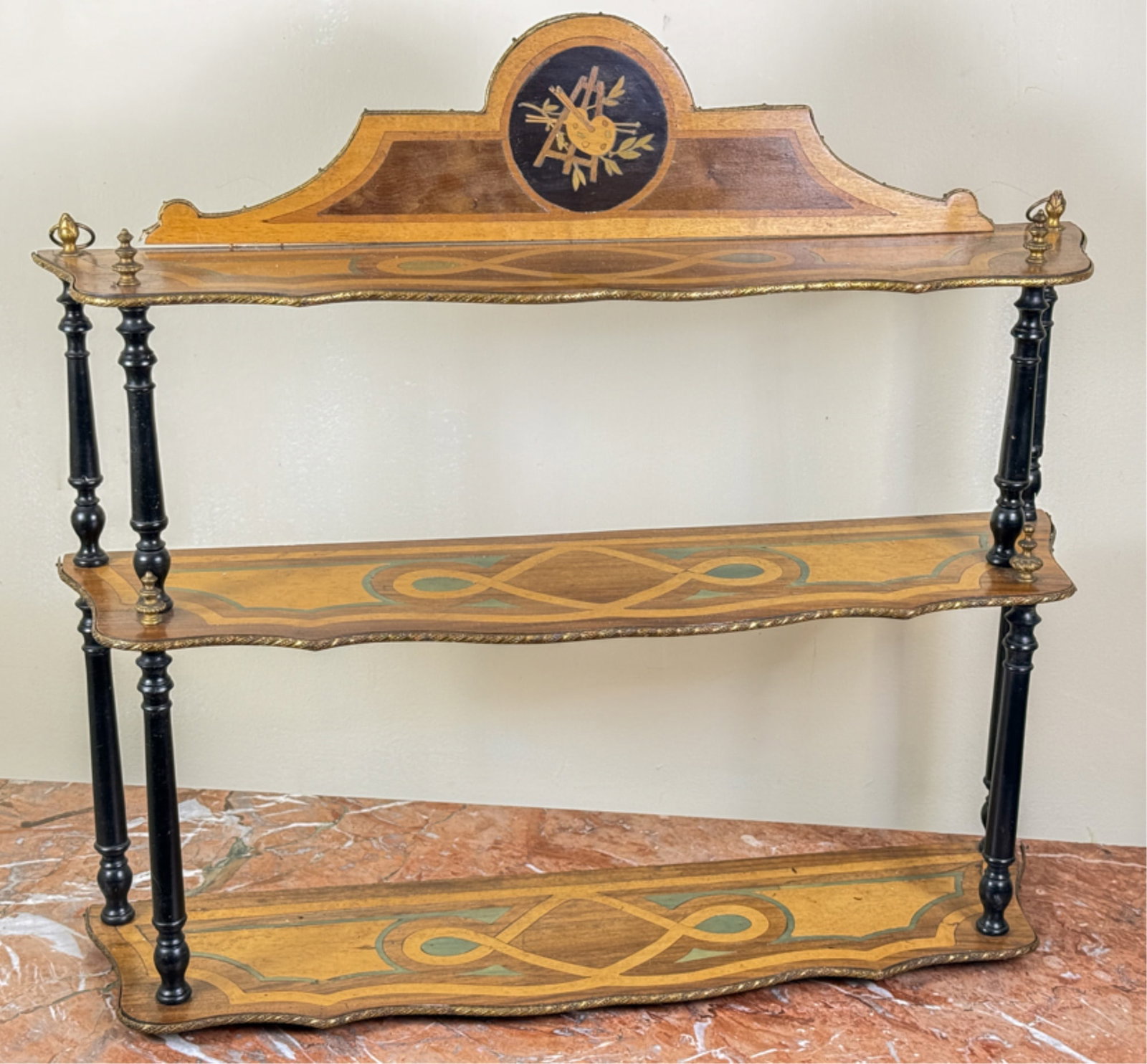 AESTHETIC MOVEMENT (3) TIERED HANGING SHELF: With easel and pallet inlaid crest. Brass moldings and finials. 23 1/2 x 26 1/2 inches.