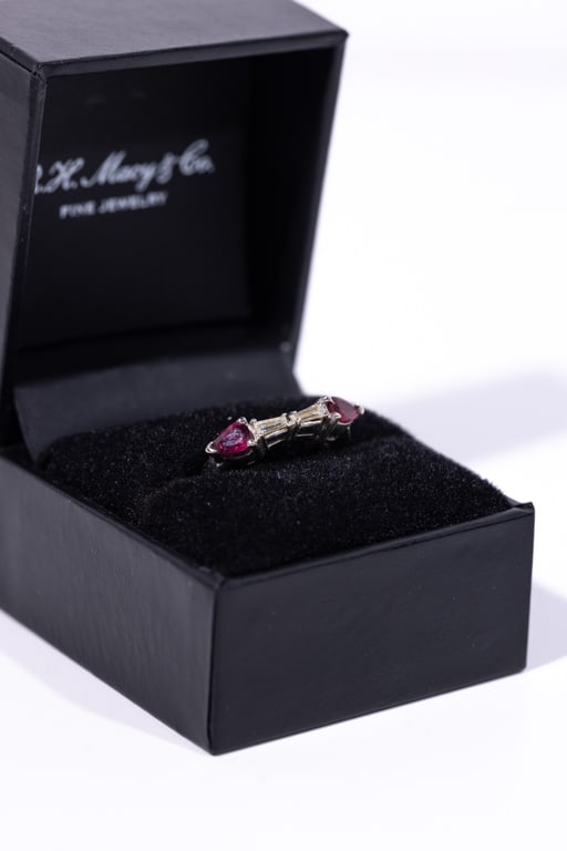 DIAMOND & RUBY WEDDING BAND IN PLATINUM SETTING: (2) Tapered baguette diamonds measuring 4 x 1 mm flanked by (2) pear shaped 4 x 5 mm rubies. Ring size 5. Gross weight 3.53 grams. Note: Matches lot 400