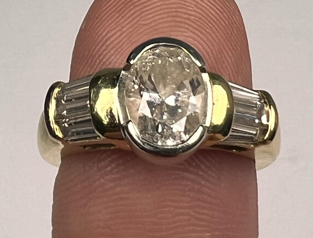 VINTAGE 18K GOLD DIAMOND RING: 1 1/2 carat central oval cut diamond, I1 and J color. Flanked by diamond baguettes totaling approx 1/2 carat. Band marked 18k. Size 6. 9.4 grams.
