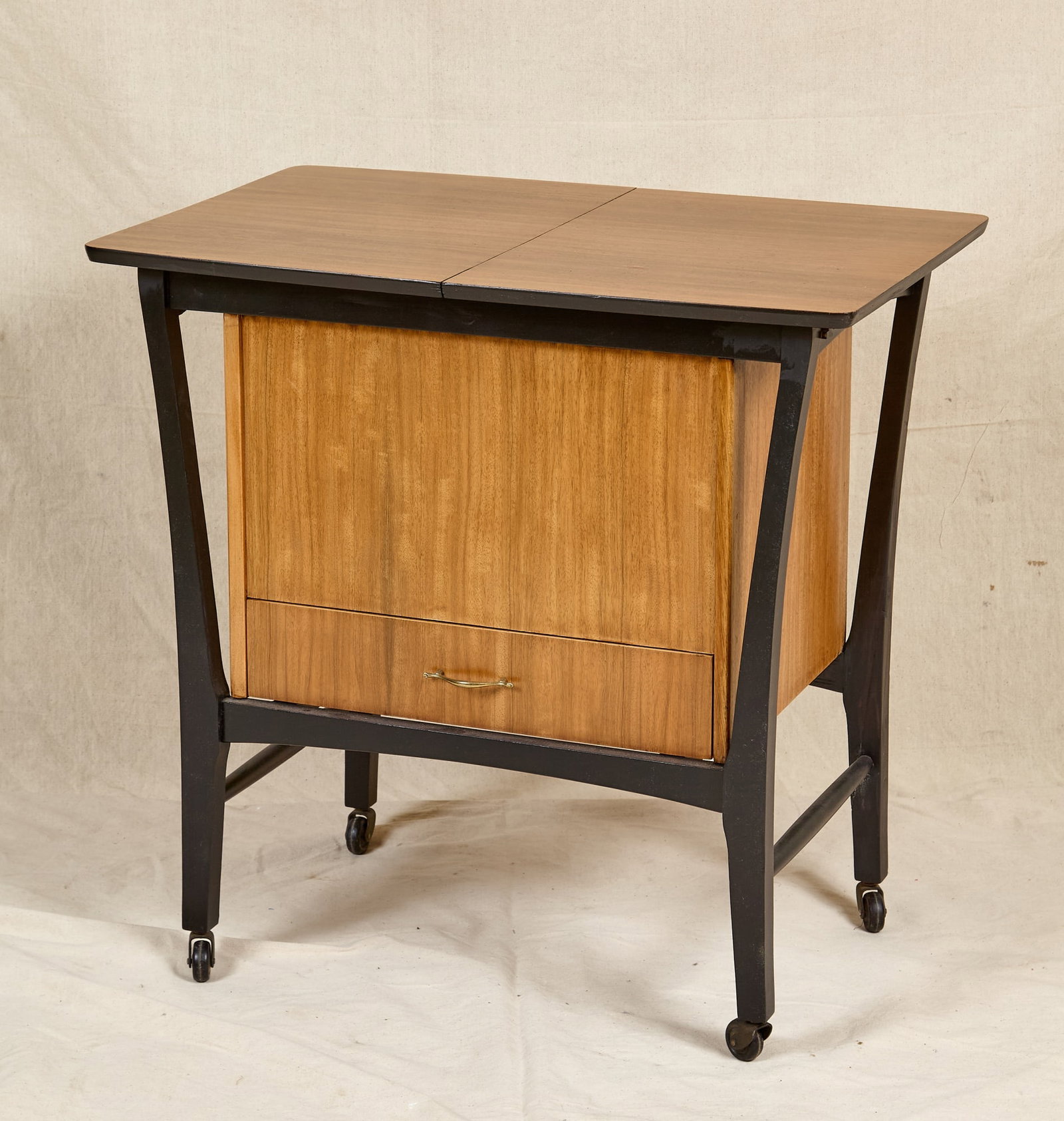 MID-CENTURY E. GOMME LTD SEWING TROLLEY: Unmarked. Top slides open to removable sliding tray and large compartment above a single drawer. 29 x 30 x 20 inches (including casters)