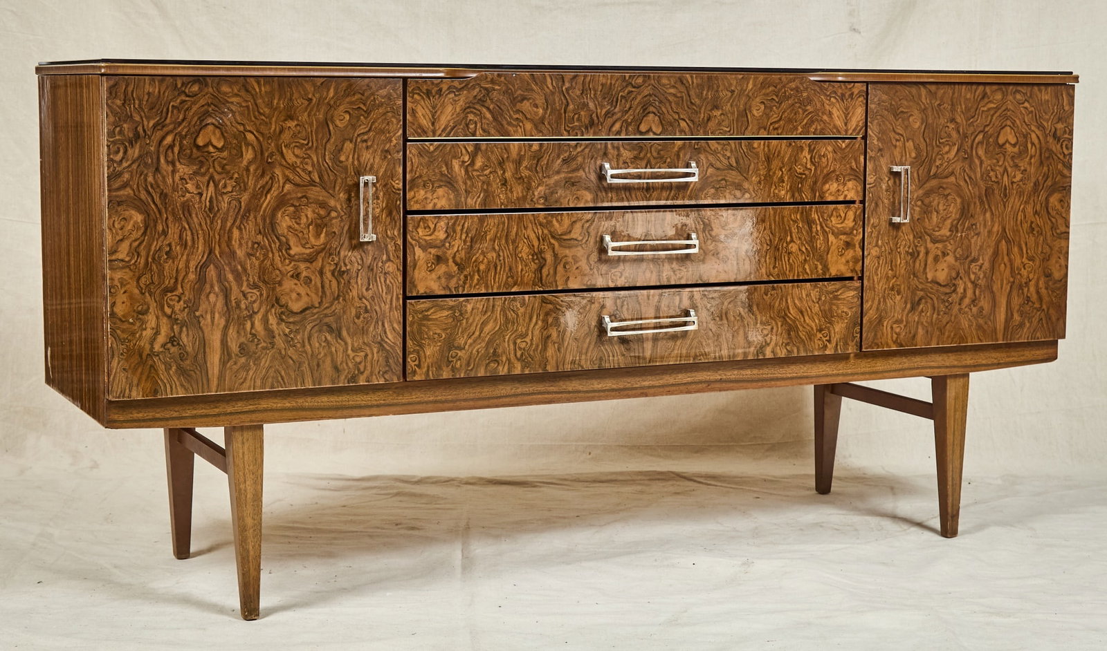 BEAUTILITY MID-CENTURY BURLWOOD CREDENZA: Applied composite obsidian top, burlwood veneer with high polish. 30 1/2 x 63 1/2 x 18 inches.