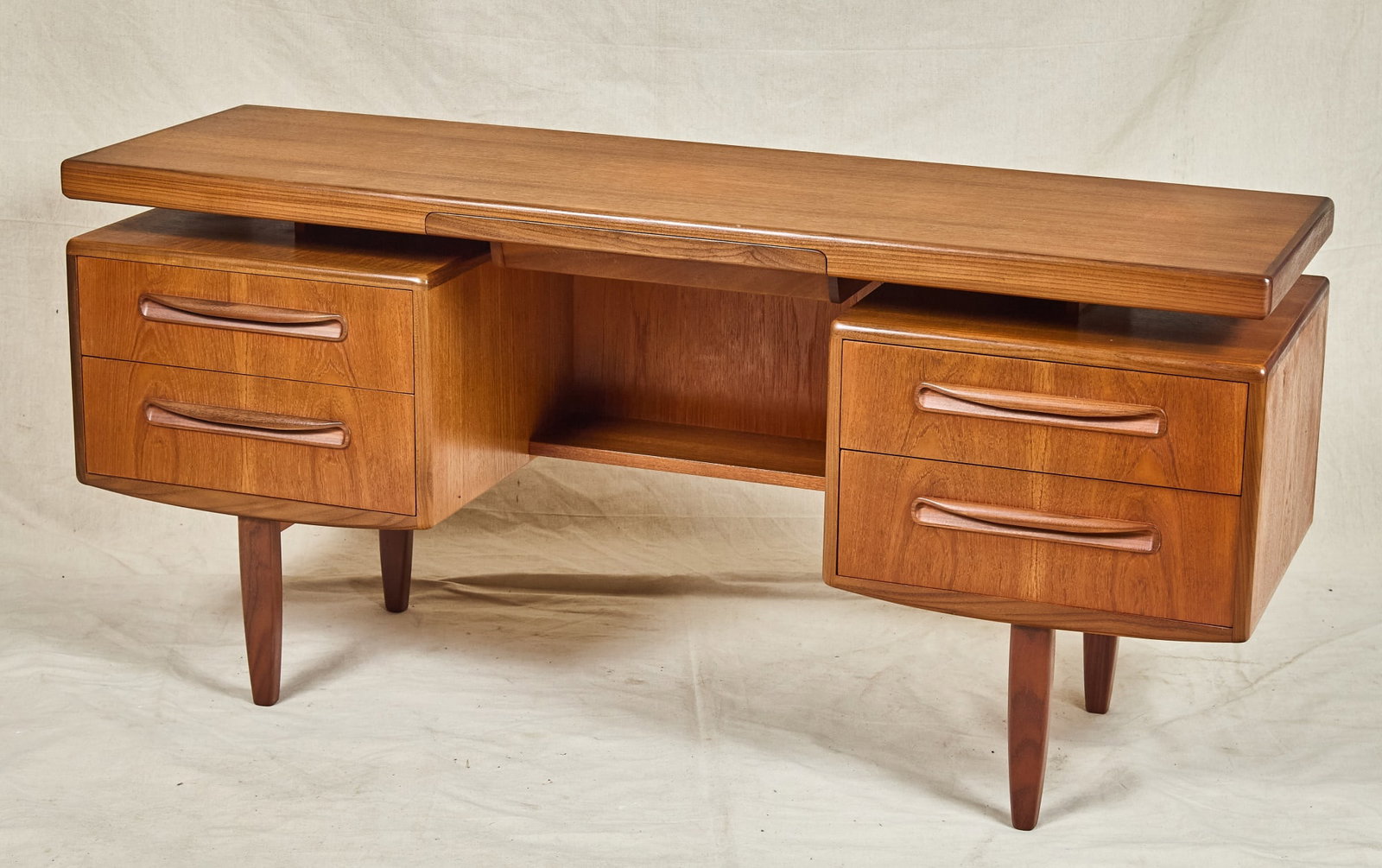 MID-CENTURY G PLAN "FRESCO" DESK: Floating top with hidden drawer, (2) banks each with (2) drawers, raised on tapered legs. 27 1/2 x 59 1/2 x 18 inches.