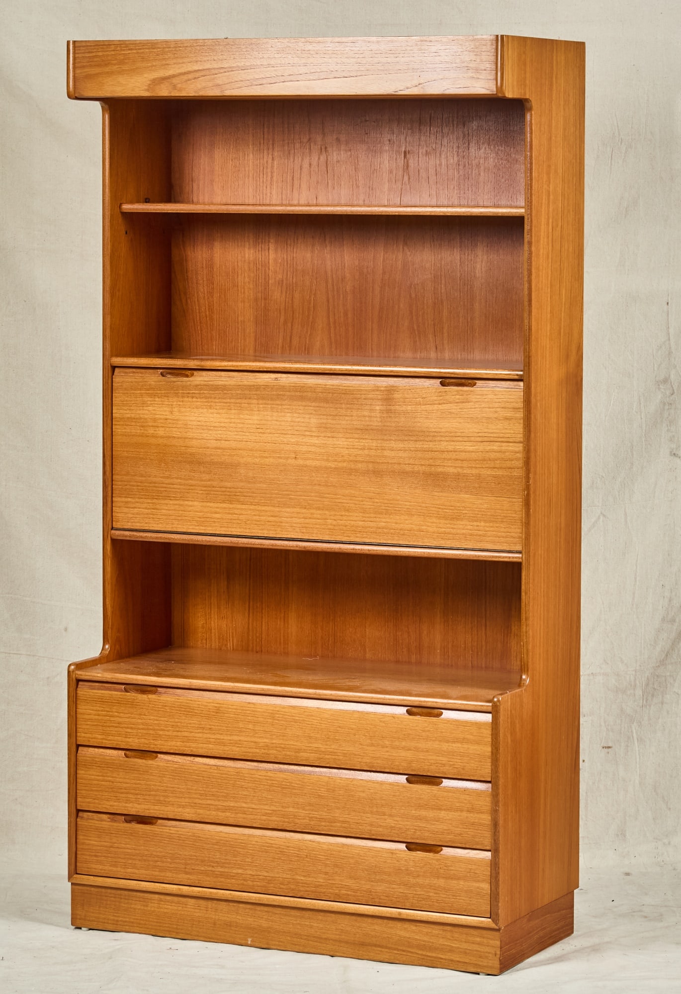 MID-CENTURY TURNIDGE TEAK CABINET/BOOK SHELF: Case with overhead hood light, shelving, fall front cabinet, and lower drawers. 68 x 36 x 13 inches.